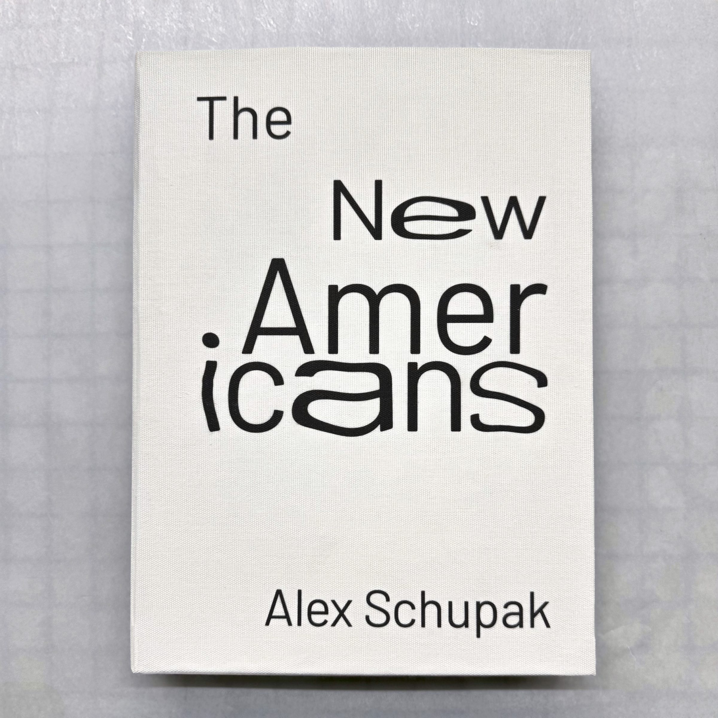 The white cloth hardcover of The New Americans by Alex Schupak, the title set in scattered black type.