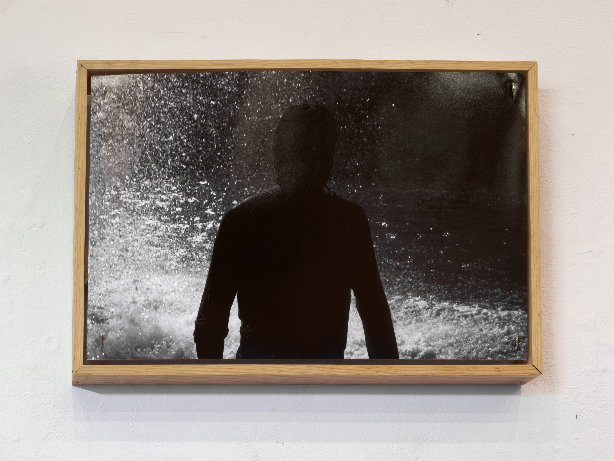 Detail: a framed black-and-white photograph of a backlit figure standing before a spray of water.