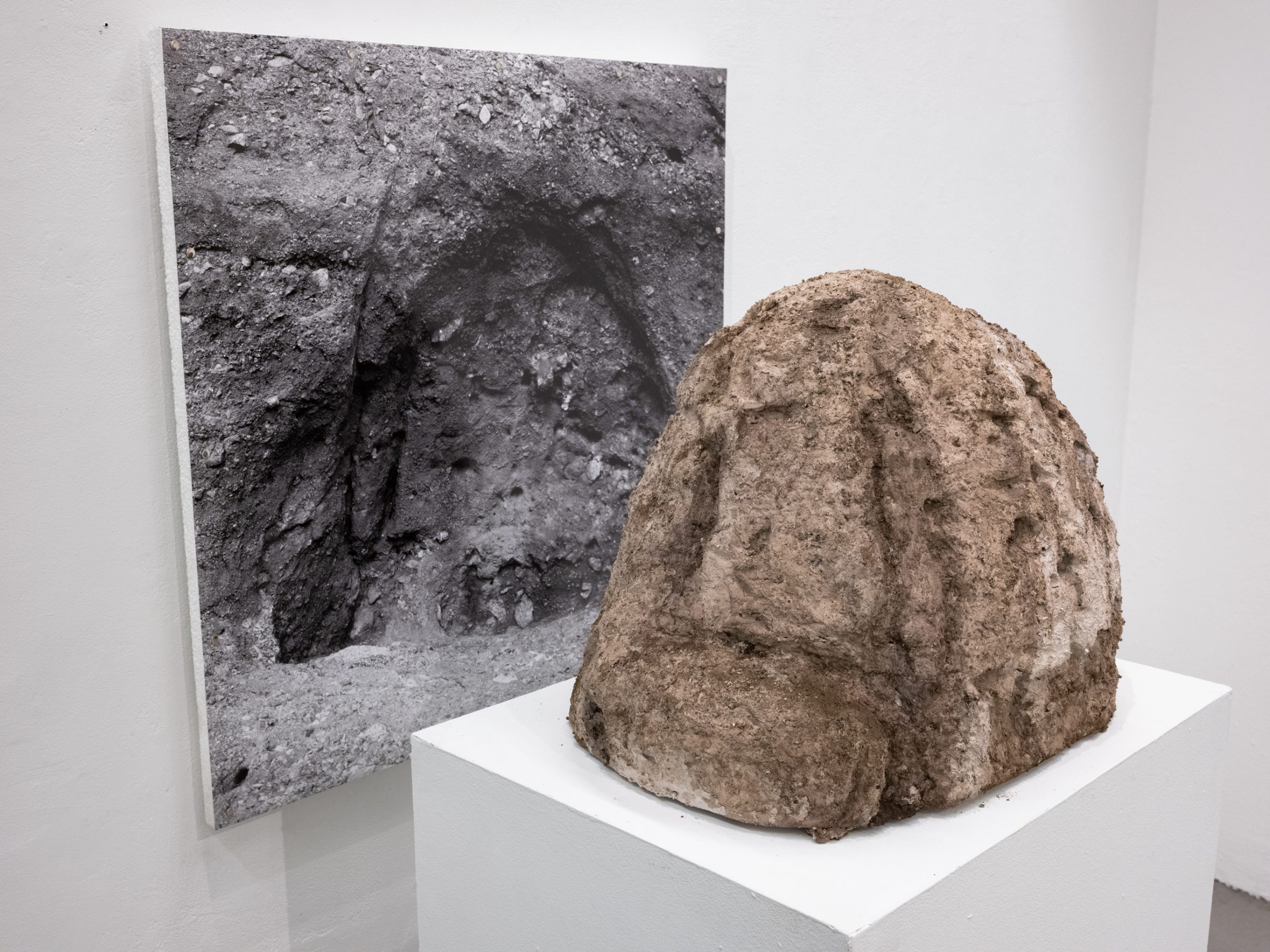 The boulder sculpture and the photograph of the dug hole seen together from an angle.